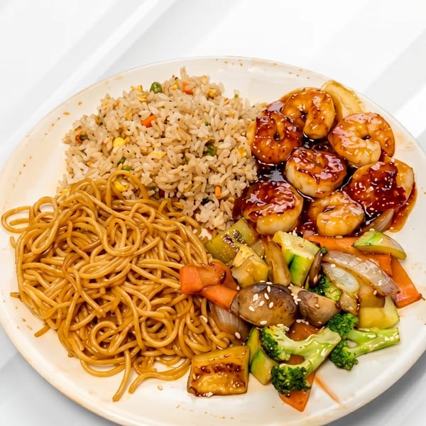 A plate of hibachi shrimp, fried rice, lo mein noodles, and mixed vegetables with sesame seeds.