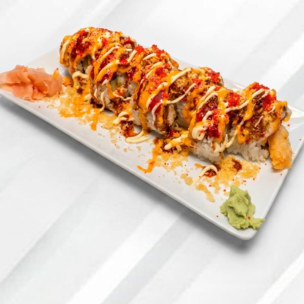 A long plate of sushi rolls topped with orange and white sauces, red roe, and tempura flakes.